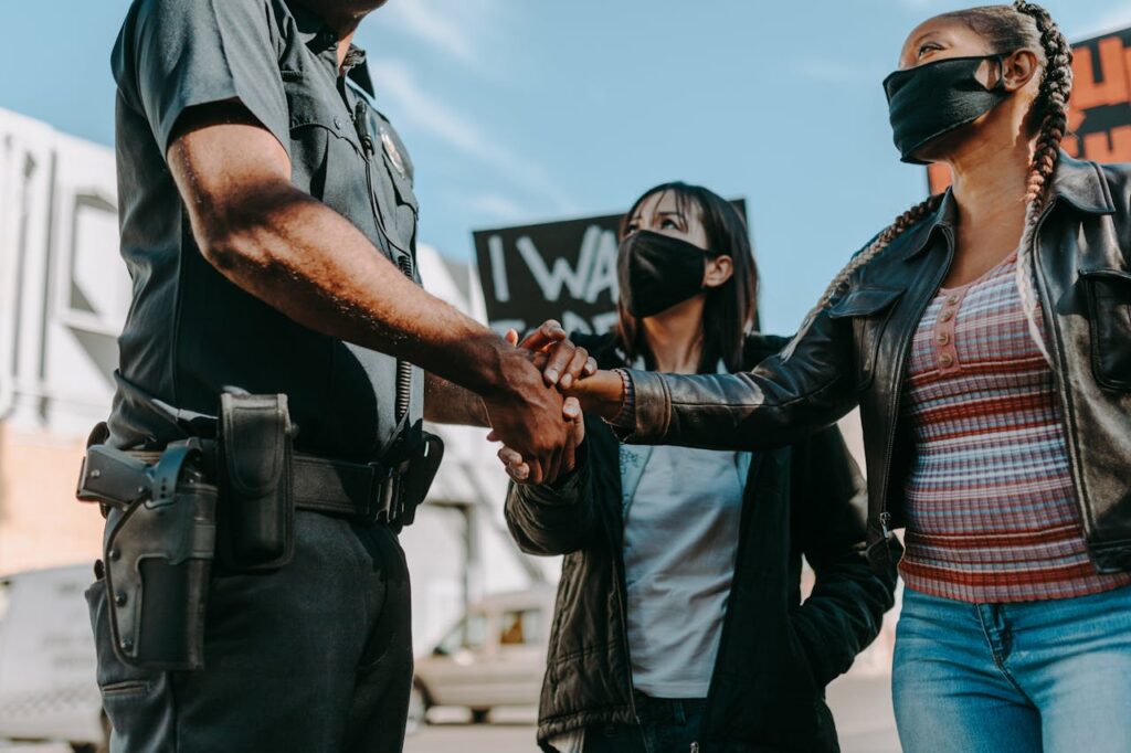 Police officer shaking hands with protesters during a peaceful demonstration.